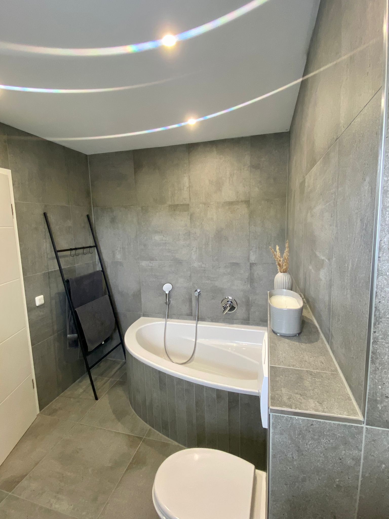 Bad mit Badewanne und grauen Fliesen